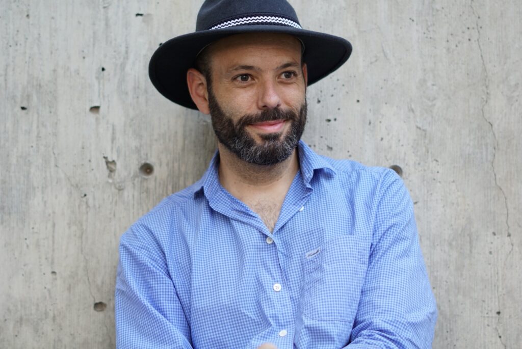 Bend Oregon Marketing Consultant, Andy Vaughn wearing a blue hat and shirt against a concrete wall